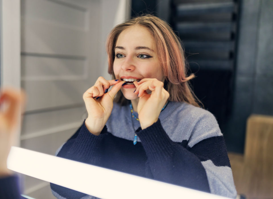 Patient placing a clear retainer in front of a mirror at Dr Dev Orthodontics