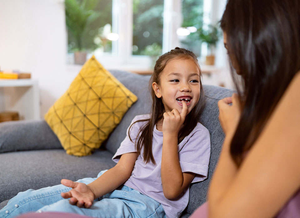A young child smiling with a gap where a baby tooth has come out